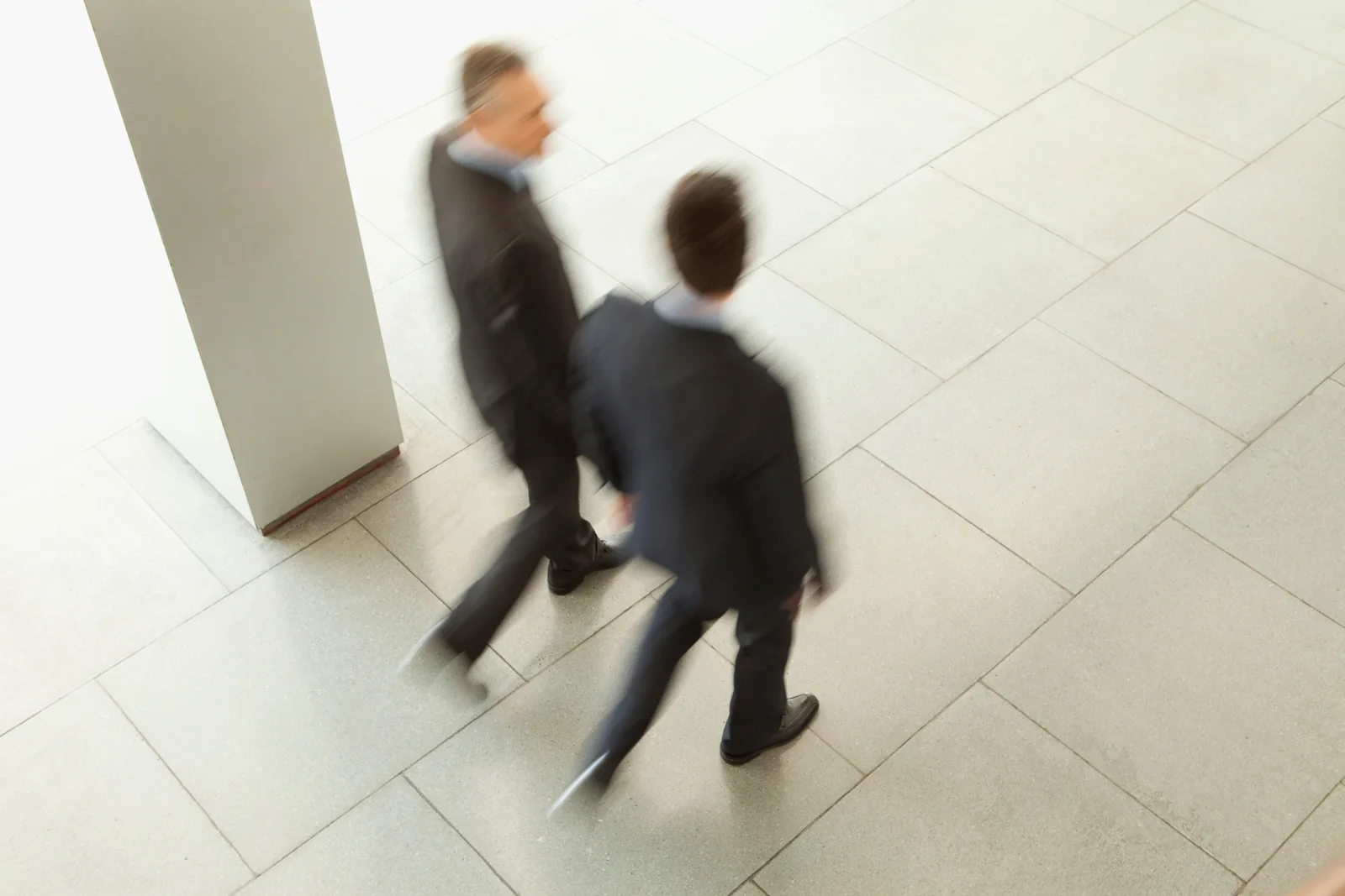 Motion-blurred figures walking through an office corridor